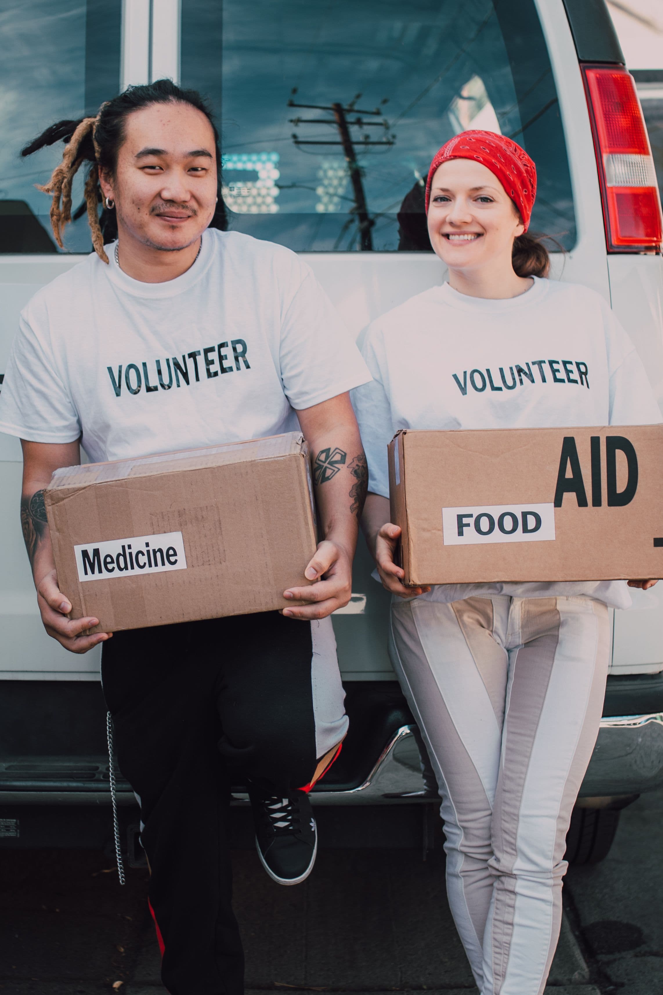 Two smiling volunteers holding boxes of food and aid donations